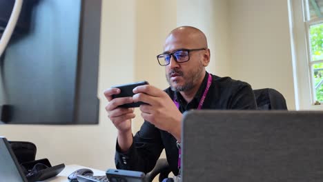 Retrato-De-Un-Hombre-Calvo-Con-Anteojos-Usando-Un-Teléfono-Inteligente-Dentro-Del-Lugar-De-Trabajo