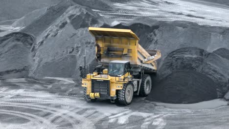 Large-dump-truck-unloading-gravel-in-stone-quarry-during-sunny-day