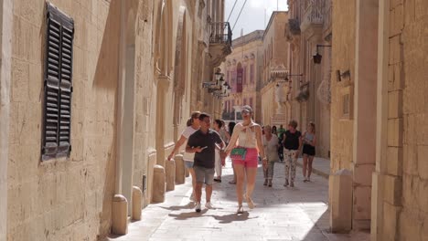 Travelers-and-visitors-leisurely-explore-the-quaint,-narrow-streets-of-Mdina,-Malta,-immersing-themselves-in-its-historic-charm-and-architectural-beauty