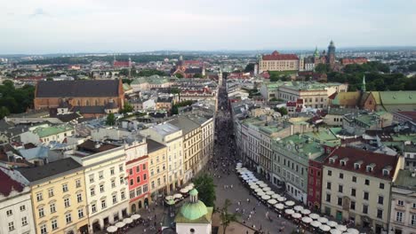 Drone-shot-of-the-main-square-of-Krakow-Old-Town,-Grodzka-Street,-crowd-of-tourists-walking-down-the-streets-of-Krakow