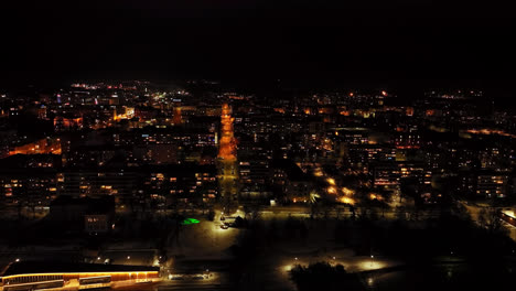 Drone-overlooking-the-night-lit-Vaasa-city-skyline,-winter-evening-in-Finland