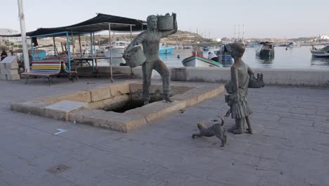 Statues-and-an-ornamental-pool-adorn-Marsaxlokk,-one-of-Malta's-picturesque-fishing-villages-and-harbors,-located-near-Valletta-in-the-southwest-of-the-island