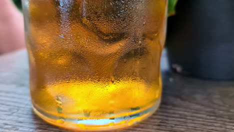 Zoom-out-shot-of-a-glass-of-beer-with-forming-bubbles-rising-placed-on-a-restaurant-table