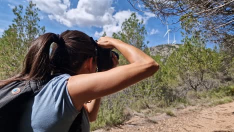 Young-brunette-girl-taking-pictures-with-camera-on-a-country-trail