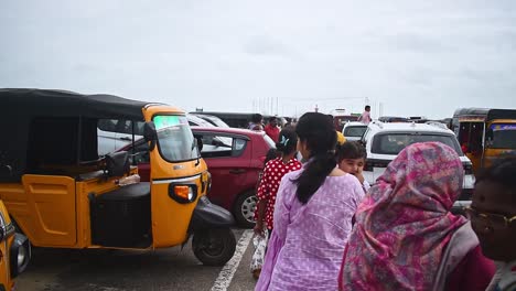 People-walks-in-the-car-parking-goes-to-the-final-destination-through-returning-crowd-of-people-and-cars