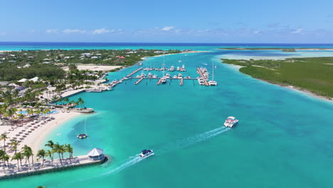 Tilt-up-aerial-4K-footage-of-a-boat-cruising-in-the-blue-waters-of-a-marina,-passing-stationary-yachts-on-the-left