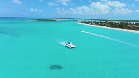 Toma-Panorámica-Circular-De-Un-Yate-Blanco-Y-Una-Lancha-Rápida-Que-Atraviesa-Las-Impresionantes-Aguas-Azules.