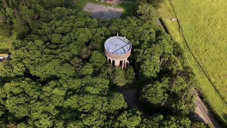 Old-Concrete-Water-Tower-Surrounded-By-Lush-Woods-Near-Countryside-Of-Essex,-United-Kingdom