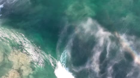 Drohnenaufnahme-Einer-Vorbeiziehenden-Welle-Von-Oben,-Die-Einen-Regenbogen-In-Der-Gischt-Hinterlässt