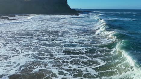 Drone-track-around-wave-wake-crashing-on-beach