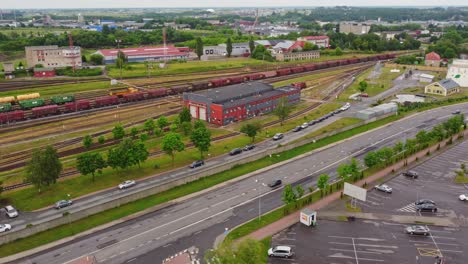 Freight-train-leaving-depot-of-Klaipeda-city,-aerial-view