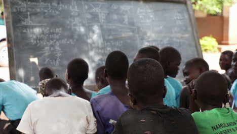 Pupils-sitting-and-listening-lecture-in-an-outdoor-classroom-in-Kampala,-Uganda