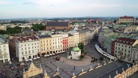 Toma-De-Drones-De-La-Plaza-Principal-Del-Mercado-Del-Casco-Antiguo-De-Cracovia,-Multitud-De-Turistas-Reunidos,-Visitando-La-Plaza-Principal-Del-Mercado