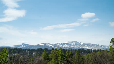 Timelapse-De-Montañas-Cubiertas-De-Nieve-Frente-A-Un-Bosque-De-Abetos-Al-Sol-Durante-El-Invierno-En-Noruega