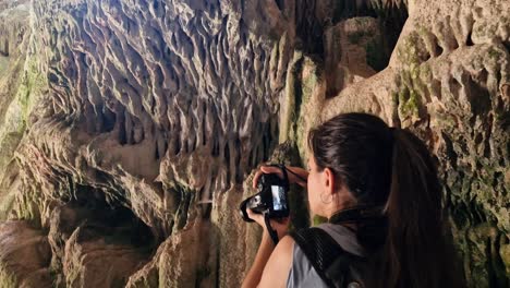 Brunette-curious-woman-taking-pictures-with-camera-inside-a-cave