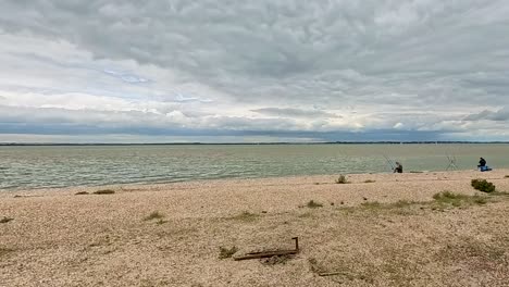 Pescando-En-La-Orilla-De-La-Playa-De-Shell-De-La-Central-Eléctrica-Bradwell-En-Essex,-Reino-Unido