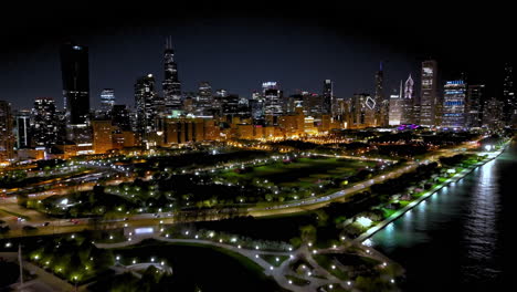 Aerial-view-approaching-the-illuminated-Grant-Park,-night-in-South-Loop,-Chicago