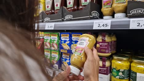 Brünettes-Mädchen-In-Einem-Supermarkt,-Das-Ein-Glas-Mango-Curry-Sauce-Aufhebt