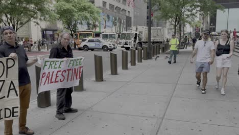 A-ground-level-shot-of-three-men-holding-pro-Palestine-signs-on-the-sidewalk-in-front-of-St