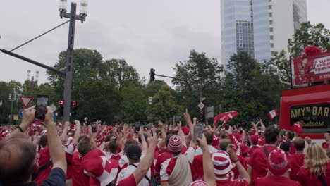 Huge-Danish-fans-crowd-cheering-and-party-going-on-with-Dannebrog-bus-approaching-at-EURO-Cup-in-Frankfurt,-Germany