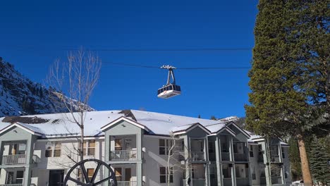 Lake-Tahoe-Ski-Resort,-California-USA,-Aerial-Tram-Gondola-Moving-Above-Olympic-Village-Building-on-Sunny-Winter-Day