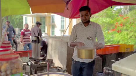 Tea-seller-at-roadside-shop-skillfully-brewing-aromatic-chai-in-large-metal-pots