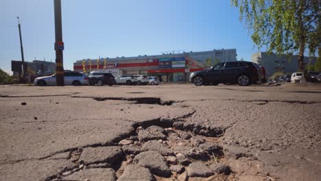 Footage-captures-a-parking-lot-for-a-shopping-center-in-Eastern-Europe-with-broken-asphalt-and-numerous-holes,-highlighting-infrastructure-issues