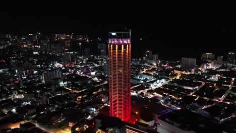 Drone-orbiting-the-night-lit-Komtar-Tower,-nighttime-in-Pulau-Pinang,-Malayisa