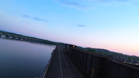 FPV-drone-shot-of-cargo-train-on-Philadelphia-and-Reading-Railroad-Bridge-at-sunset