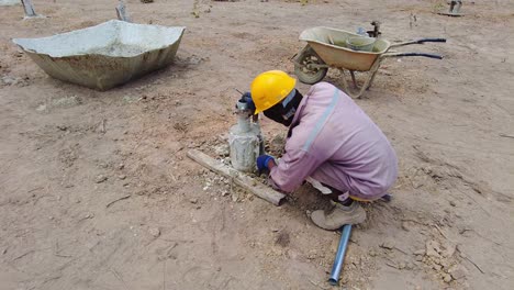 Un-Trabajador-De-La-Construcción-Técnico-Africano-En-Cuclillas-Con-Ppe-Completo-Elimina-El-Marco-Del-Molde-De-Hormigón-De-La-Pila-Solar-Fotovoltaica