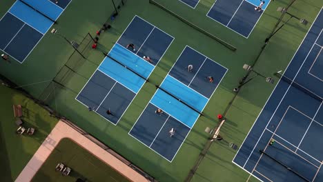 Birds-eye-aerial-view,-competitive-mixed-doubles-Pickleball-games,-pull-out-to-reveal-courts