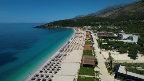 Pristine-Beach-with-White-Sand,-Sunbeds,-and-Umbrellas-for-Holidaymakers,-Crystal-Clear-Waters-of-the-Ionian-Sea-in-Livadh,-Albania
