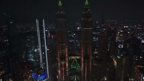 Petronas-Towers-and-the-Kuala-Lumpur-skyline,-night-in-Malaysia---pull-back,-drone-shot