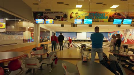 Footage-captures-adults-and-children-enjoying-a-bowling-center,-with-TV-screens-displaying-scores-and-entertainment,-creating-a-lively-atmosphere
