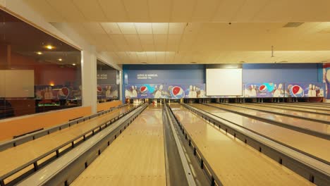 Footage-captures-a-girl-with-a-braid-and-pink-clothes-energetically-throwing-an-orange-ball-on-a-bowling-alley,-enjoying-a-recreational-moment