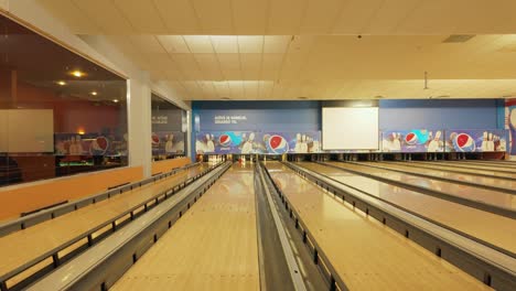 Das-Filmmaterial-Zeigt-Ein-Mädchen-Mit-Zopf-Und-Rosafarbener-Kleidung,-Das-Energisch-Einen-Orangefarbenen-Ball-Auf-Einer-Bowlingbahn-Wirft-Und-Einen-Erholsamen-Moment-Genießt