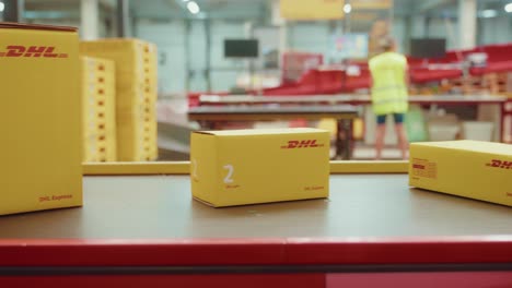 Yellow-cardboard-boxes-with-DHL-Logo-on-conveyor-belt-line-inside-warehouse