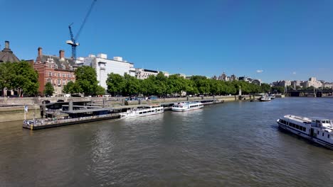 Scenic-view-of-the-River-Thames-in-London-featuring-docked-boats,-Westminster-Bridge,-and-the-iconic-city-skyline-on-a-clear-day