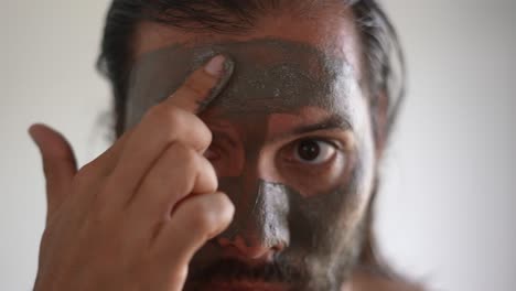 man-using-a-clay-mask-on-his-face