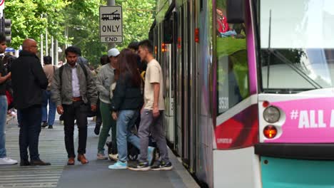 Passengers-disembarking-and-boarding-the-tram-at-the-stop-on-Swanston-street,-in-the-bustling-Melbourne-central-business-district,-concept-shot-of-population-growth