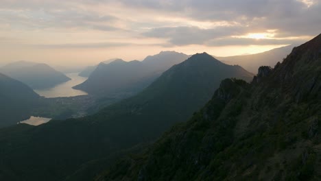 Serene-aerial-sunrise-breaking-over-a-rugged-mountain-landscape-with-a-view-of-a-tranquil-lakeside-below