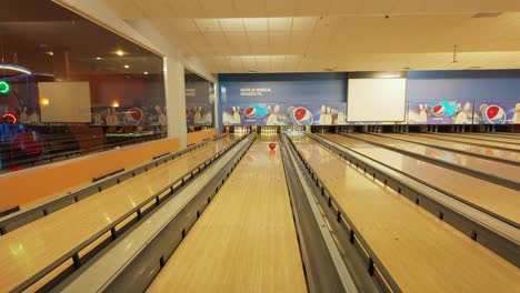 A-young-girl-dressed-in-pink-uses-a-ramp-to-throw-a-bowling-ball-at-a-bowling-center
