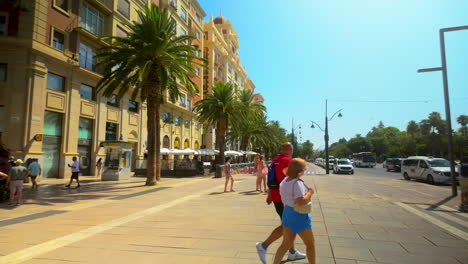 Gente-Caminando-Por-Una-Calle-Bordeada-De-Palmeras-Con-Edificios-Clásicos-Europeos-En-El-Centro-De-La-Ciudad