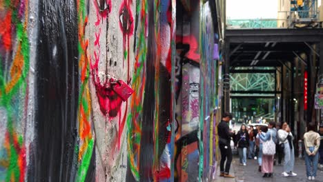 Una-Dama-Pintada-Con-Graffiti-Con-Un-Candado-En-Su-Labio-Rojo,-Calcetería,-Una-Calle-Adoquinada-Con-Una-Vibrante-Variedad-De-Murales-Artísticos-En-Las-Paredes-De-Los-Edificios,-Una-Escena-Callejera-Cultural-Creativa-En-Melbourne