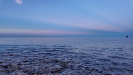 Ein-Ruhiger-Blick-Auf-Das-Meer-In-Der-Abenddämmerung-Mit-Einem-Vollmond-Am-Himmel