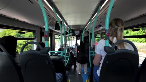 Passengers-seated-and-standing-inside-a-city-bus-during-a-daytime-ride-through-an-urban-area,-showcasing-public-transportation-usage