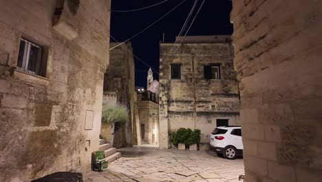 Night-Walk-on-the-Narrow-Streets-of-Matera-with-the-Beautiful-City-in-the-Background,-Basilicata-Region,-Italy