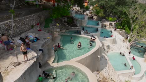 Tourists-wave-at-camera-while-relaxing-in-the-thermal-pools-at-Grutas-de-Tolantongo-resort,-Mexico,-Hidalgo-state