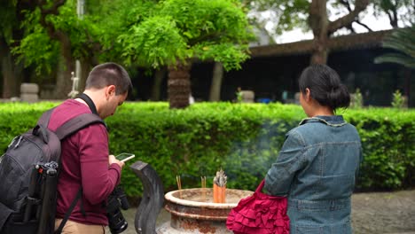 Hombre-Español-Usando-El-Teléfono-Para-Comunicarse-Con-Una-Mujer-China-Local-En-El-Patio-Del-Templo