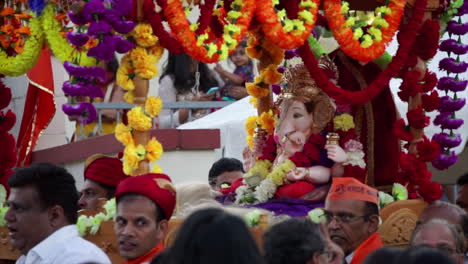 Estatua-De-Una-Deidad-Con-Cabeza-De-Elefante,-Ganesh-Es-Llevado-En-Un-Palanquín-Y-Abanicado-Por-Los-Celebrantes.